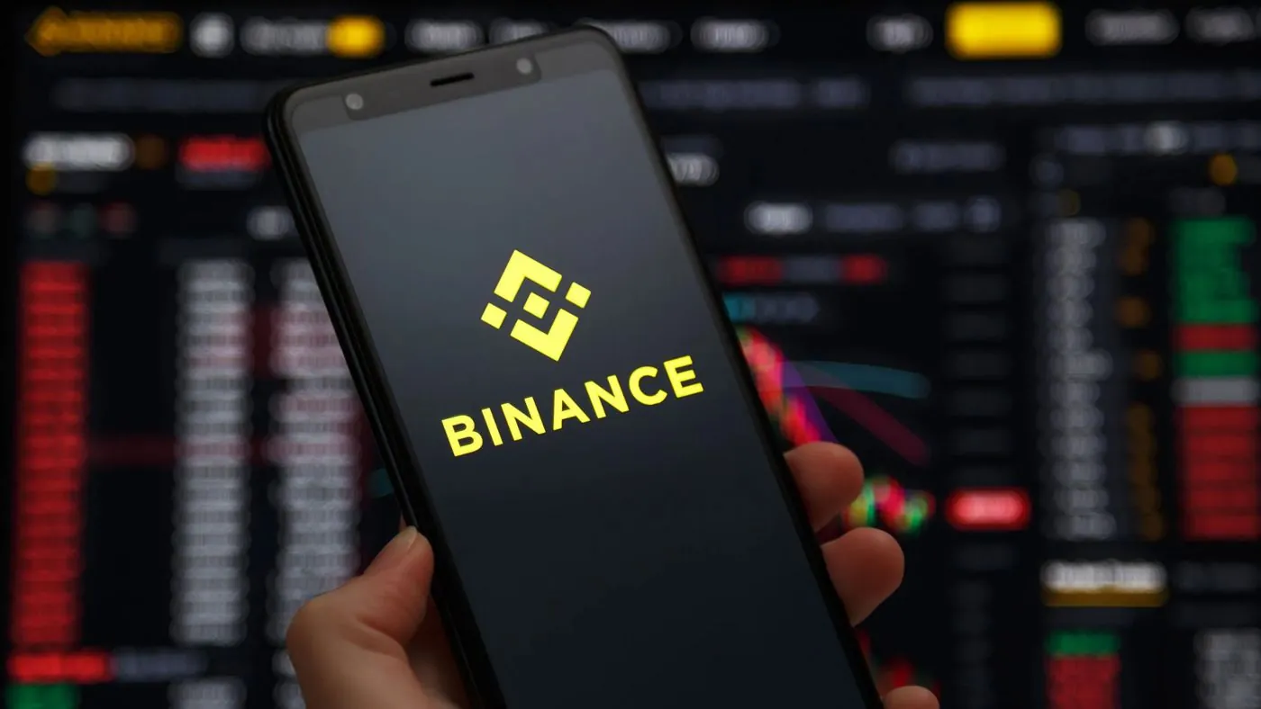 Teléfono con la app de Binance abierta frente a una pantalla de precios